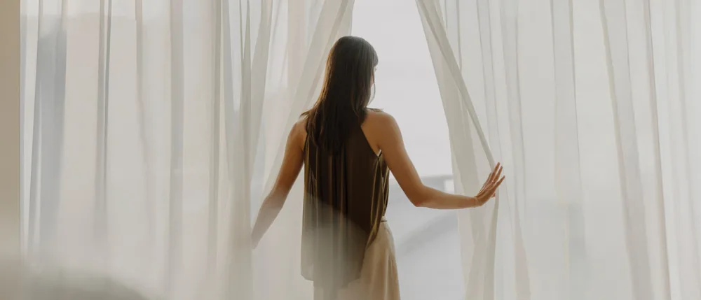 Guest opening the curtains in a Sands Premier room at Marina Bay Sands